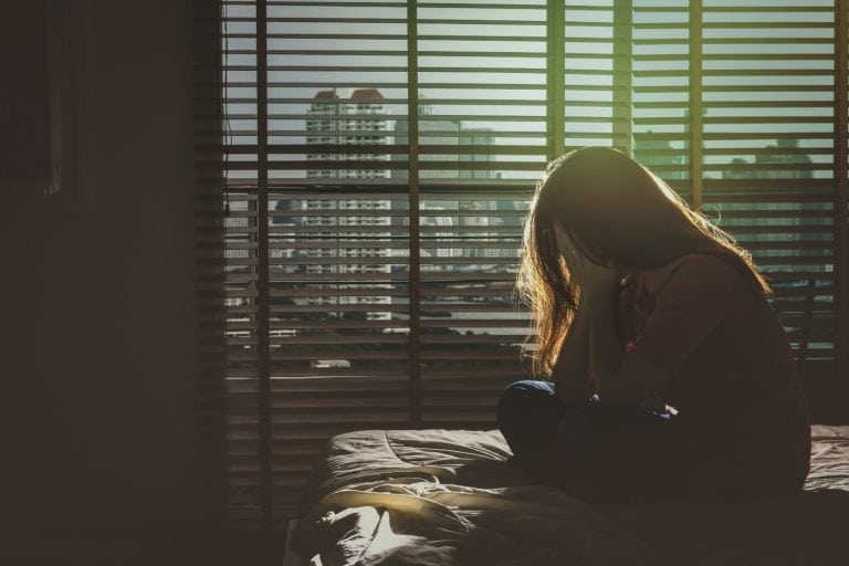image of a woman sitting alone in a dark room, concept of mental health, eating disorders