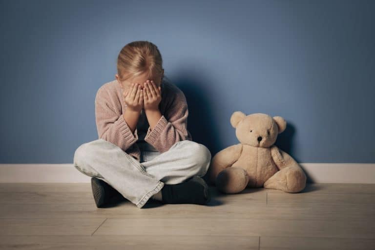 Sad Child Crying with Face in Hands Sitting on Floor