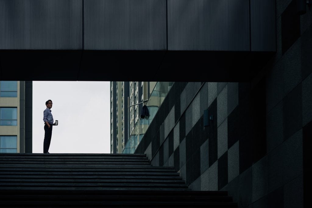man stands on a staircase between buildings in an urban setting