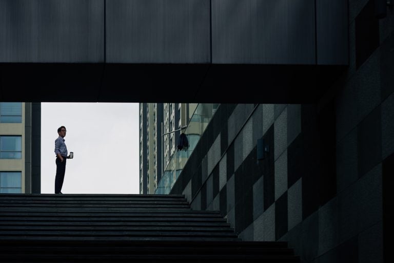 man stands on a staircase between buildings in an urban setting
